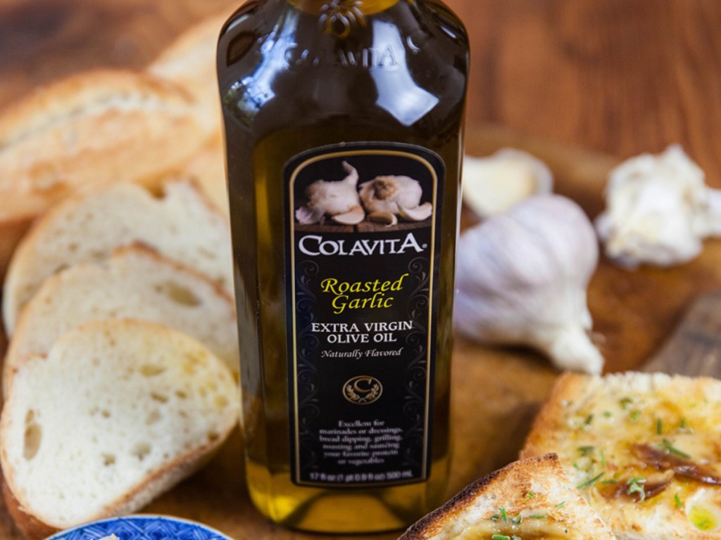 32oz Bottle of Colavita Roasted Garlic Olive Oil next to fresh basked bread and garlic cloves