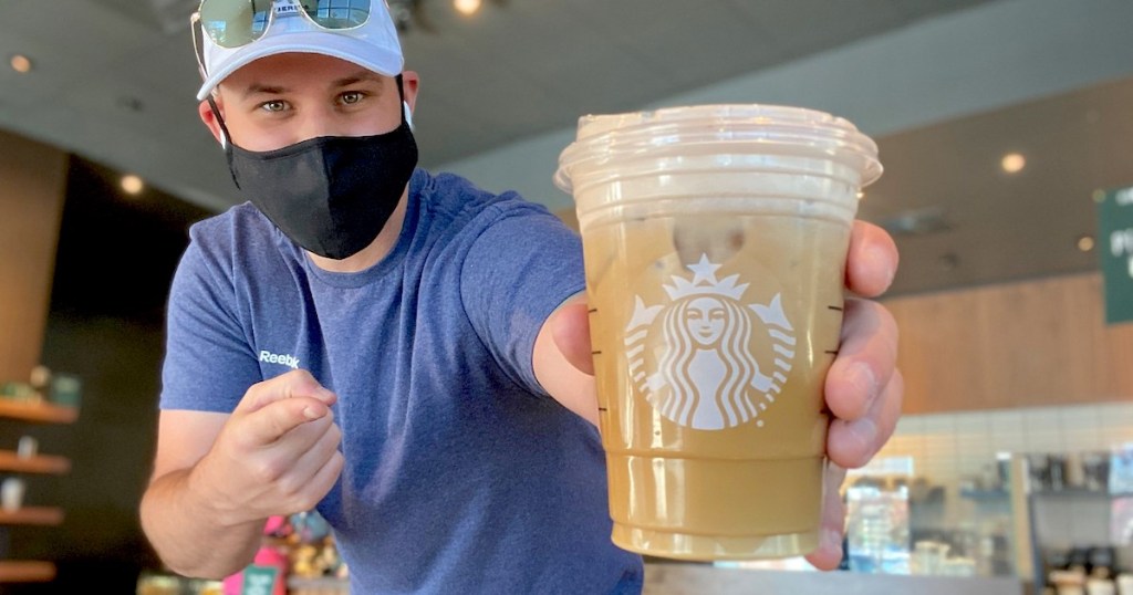 man holding a starbucks cup with coffee inside