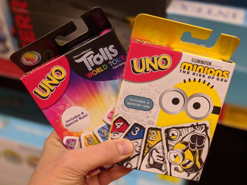 hand holding mattel UNO Trolls and UNO Minions card games