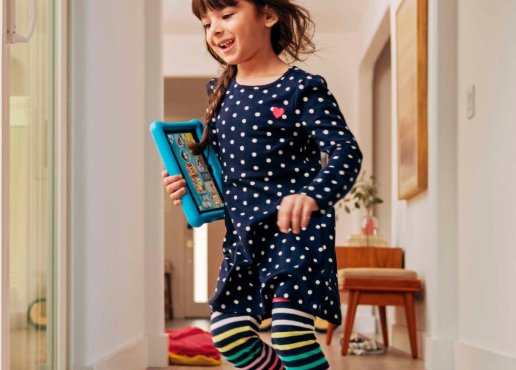 girl holding blue kindle fire while walking through the house