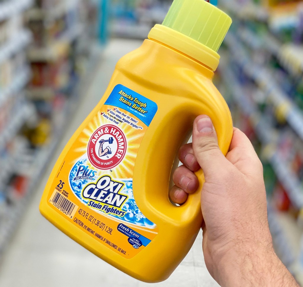 person holding up a yellow bottle of arm & hammer laundry detergent