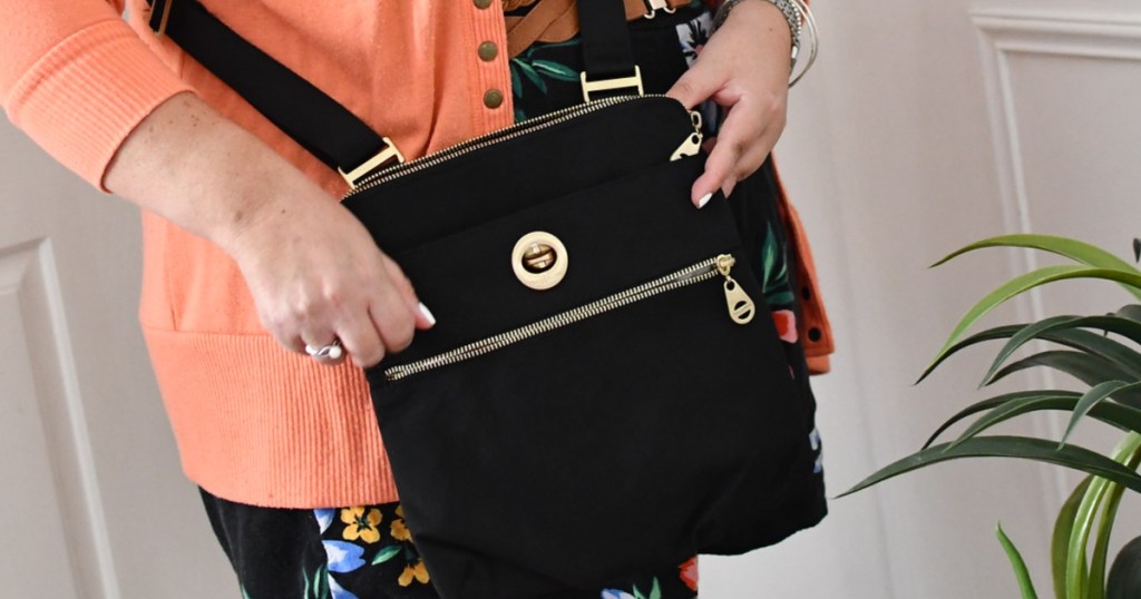 woman holding a black and gold colored crossbody bag