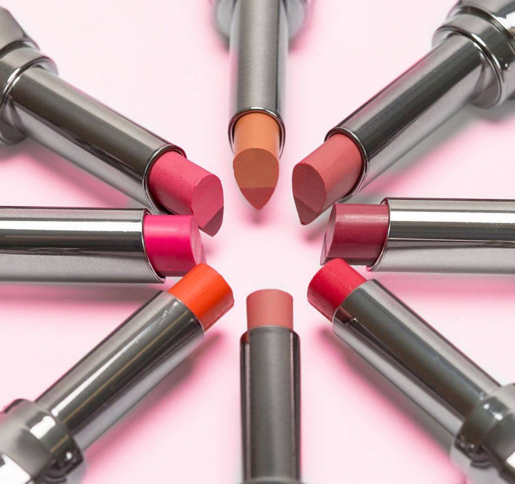 lipsticks in silver tubes arranged into a circle on a pink background