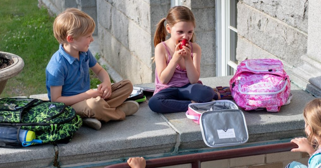 high sierra backpacks and lunchboxes kids eating on wall