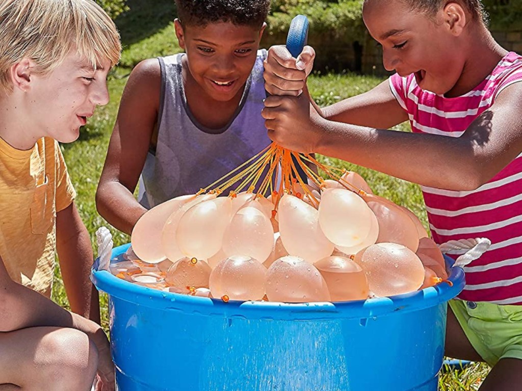 three children around tub of orange water-filled balloons