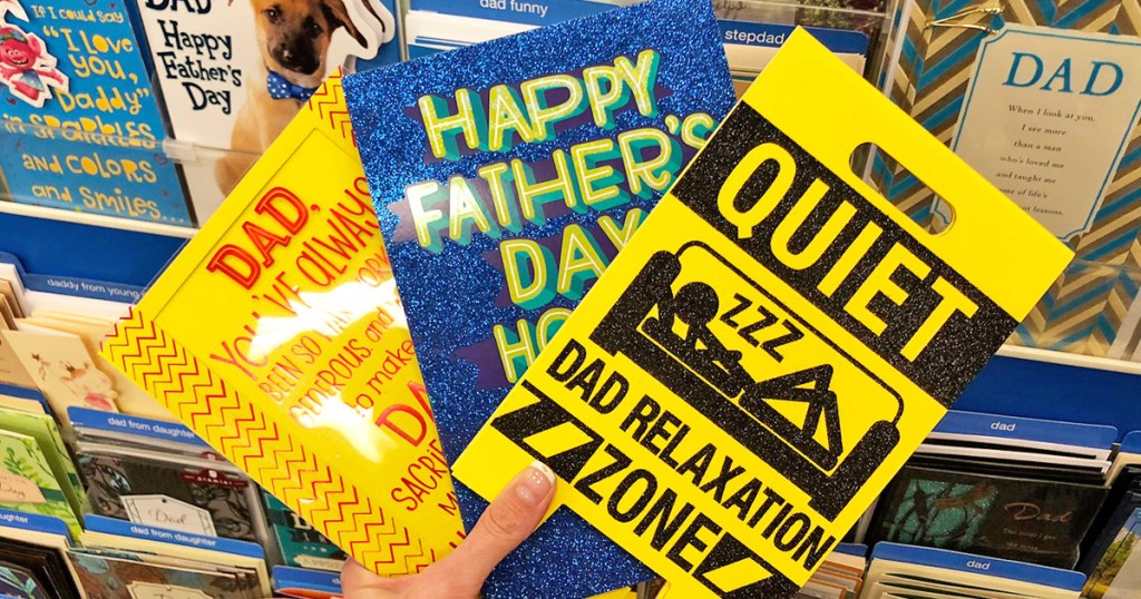 person holding up three father's day greeting cards
