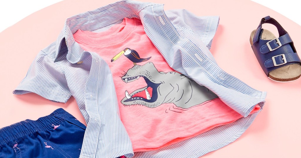 light red hippo graphic shirt layered with blue and white striped button up shirt laying on a pink background