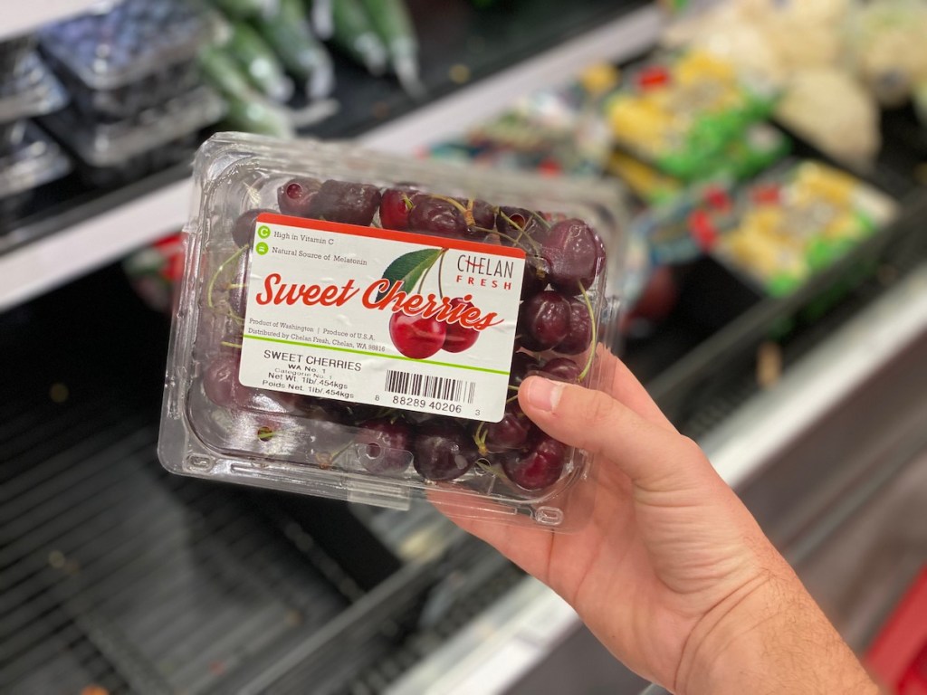 man hand holding container of fresh cherries at target