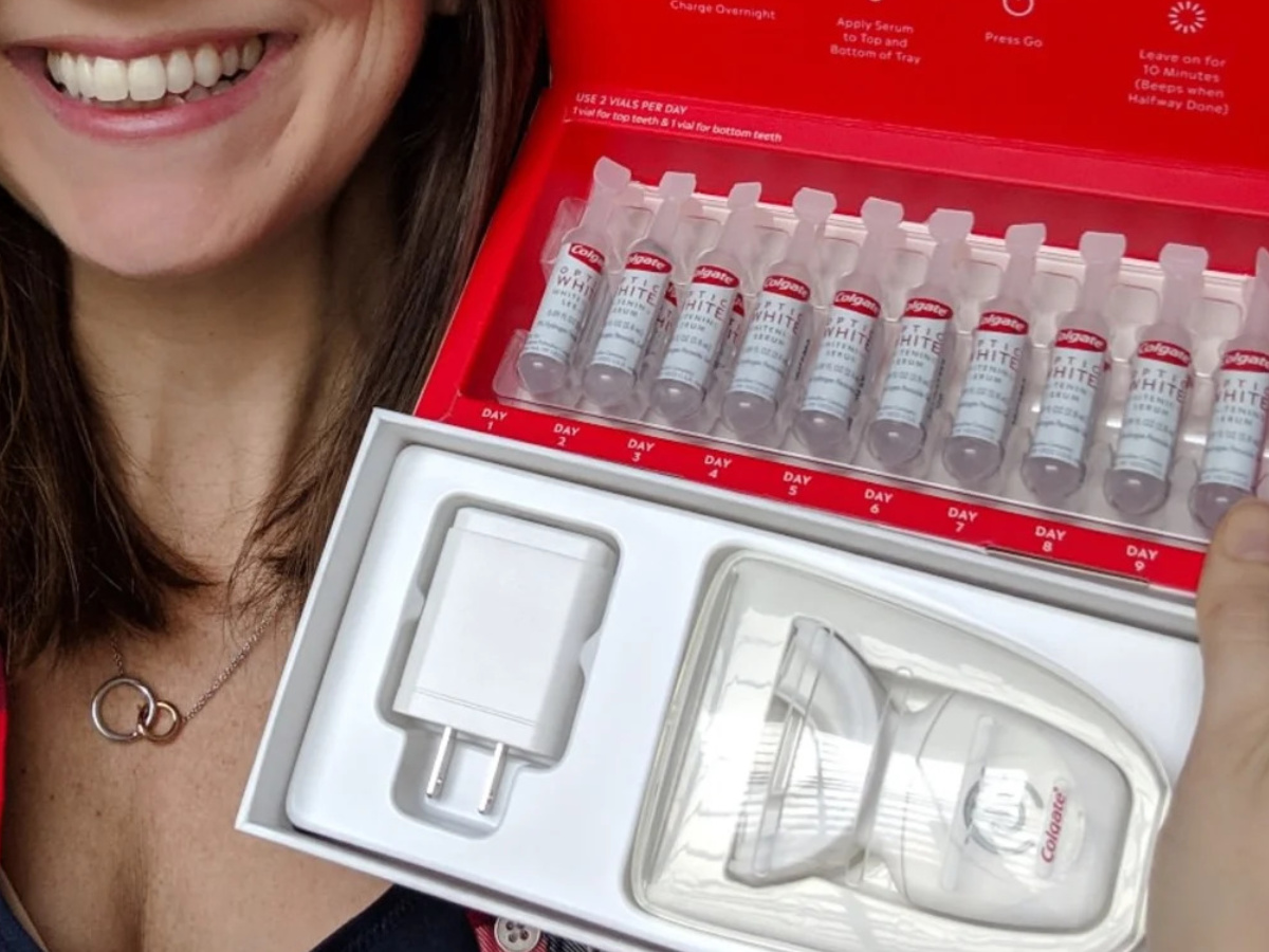 woman smiling and holding teeth whitening kit