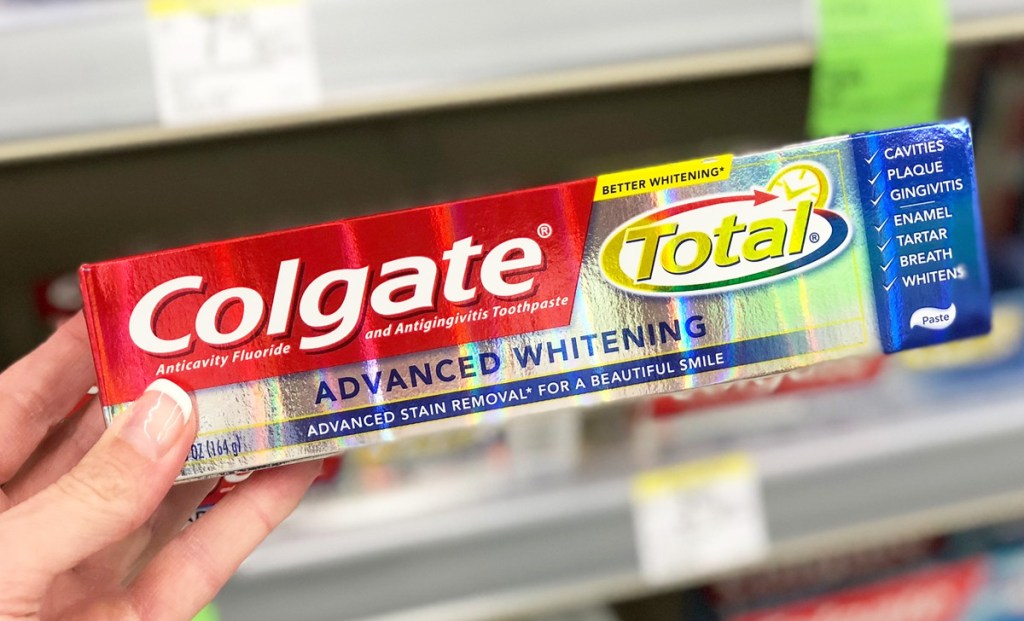 person holding up a shiny box of colgate total toothpaste
