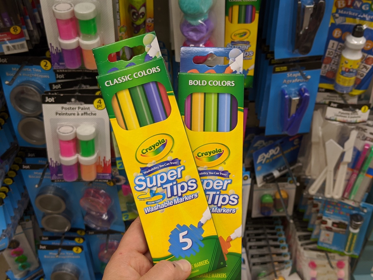 hand holding two packs of Crayola Super Tips