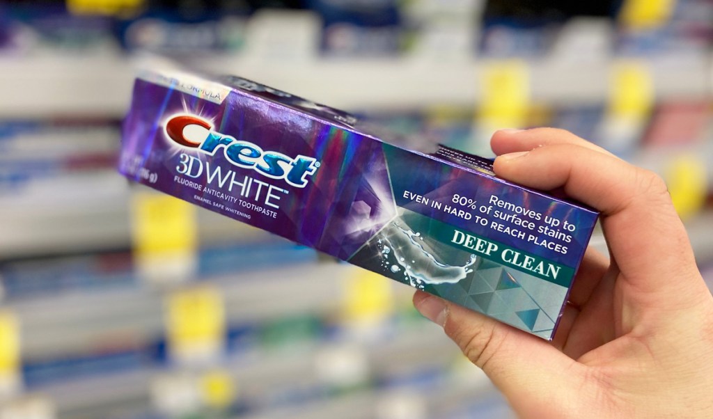 person holding up a purple box of crest 3d white toothpaste