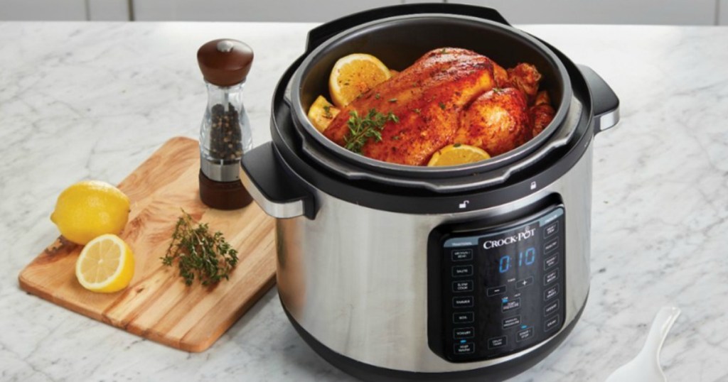 Crock-Pot with a chicken in it next to a cutting board