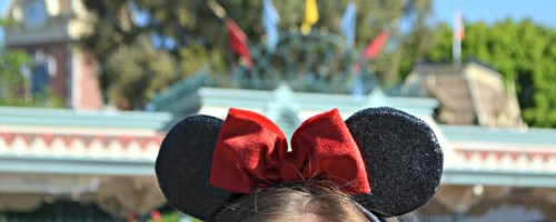 girl with black Mickey Mouse ears and red bow at Disneyland