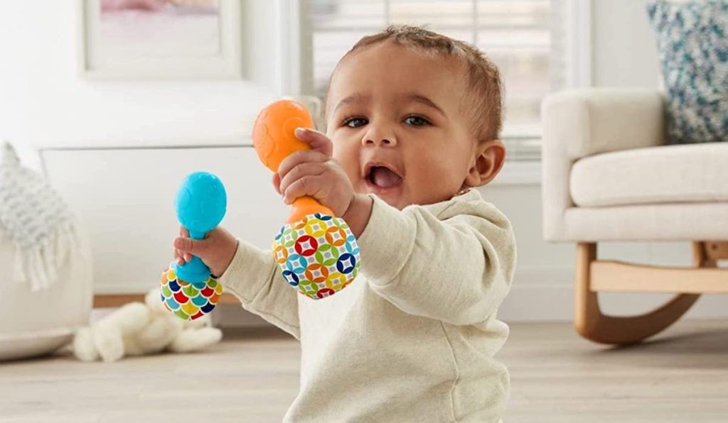 baby sitting on the floor paying with blue and orange Fisher-Price Rattle 'n Rock Maracas