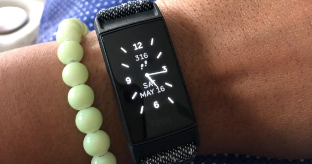 fitbit and green bracelet on womens arm