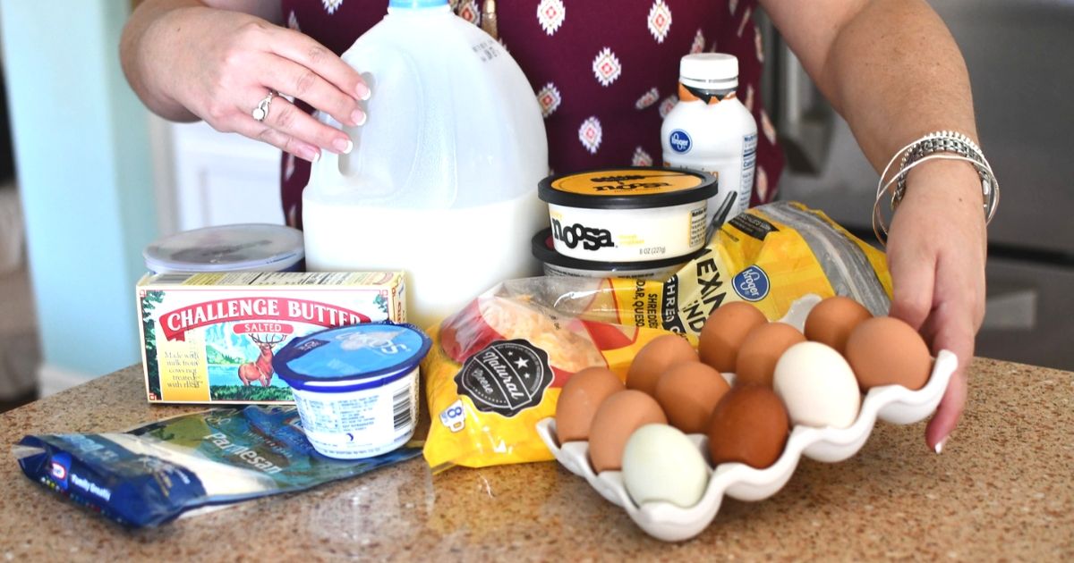 A woman standing over a kitchen counter with various dairy products