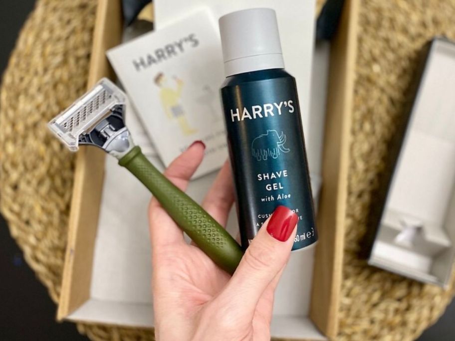 woman's hand holding a razor and shaving cream