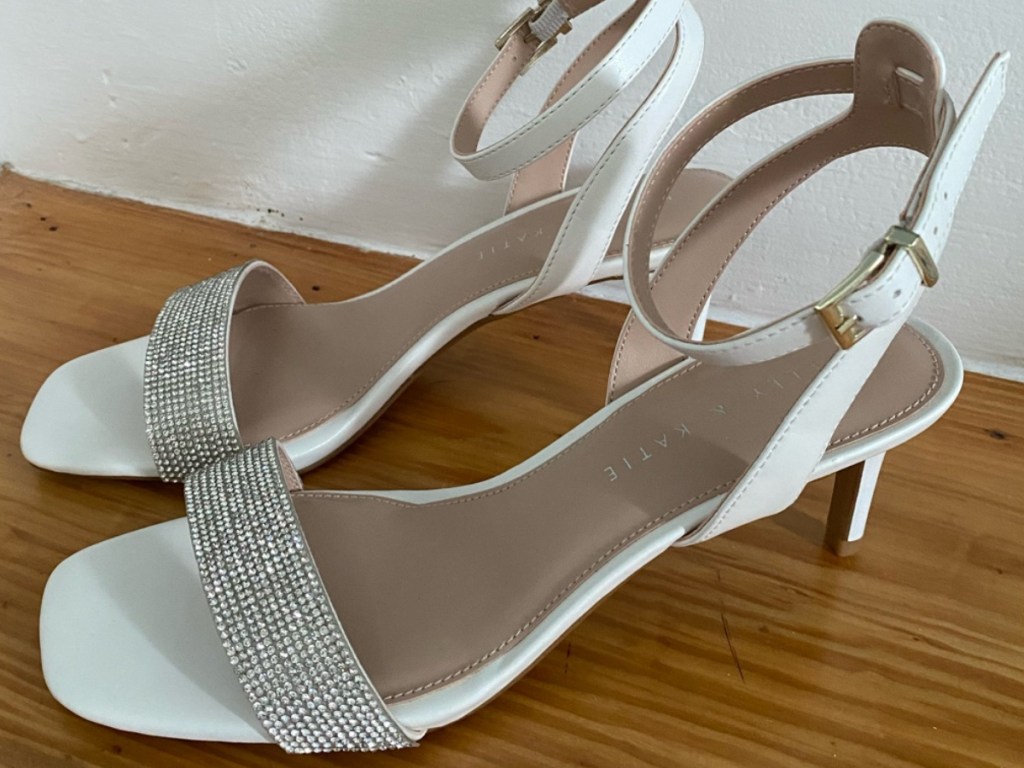 white strap heeled sandals on wood surface