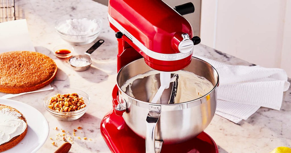 red kitchenaid mixer mixing dough in silver bowl on counter with baking ingredients around it