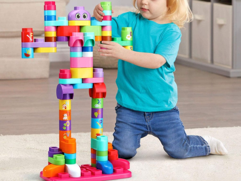 girl playing with building block set on carpet in home