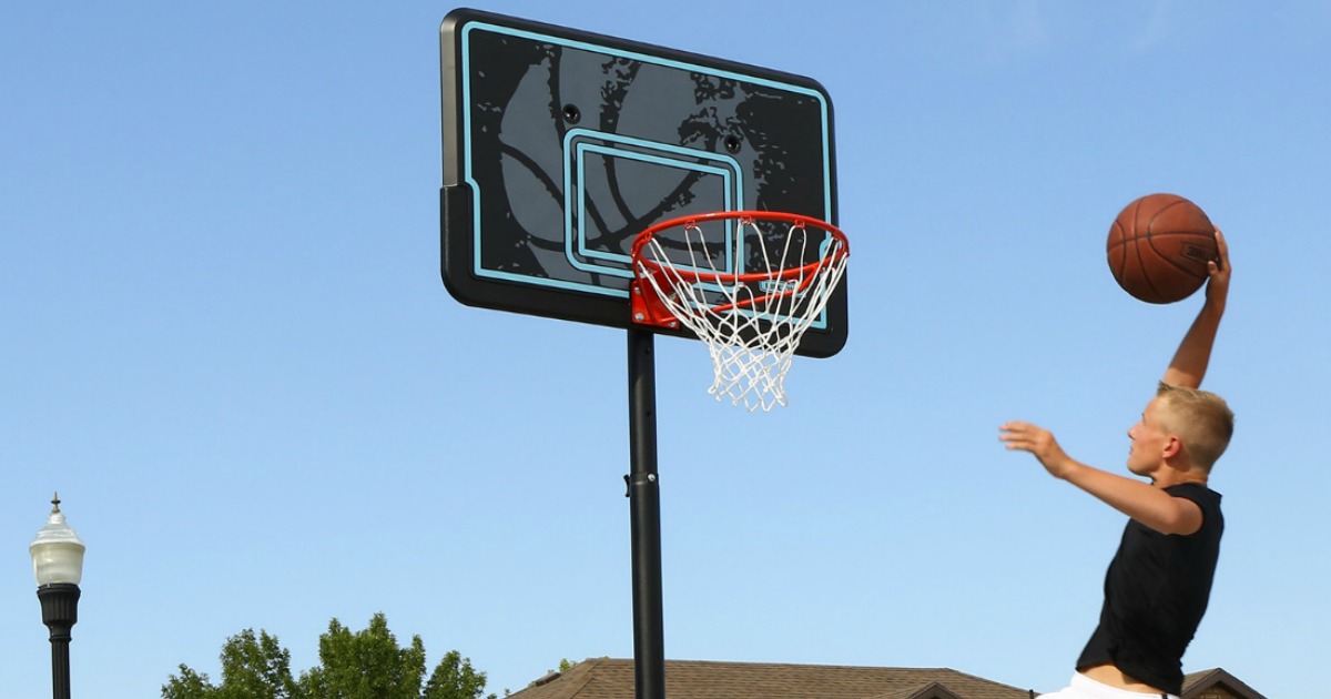 Young boy dunking basketball near outdoor basketball hoop