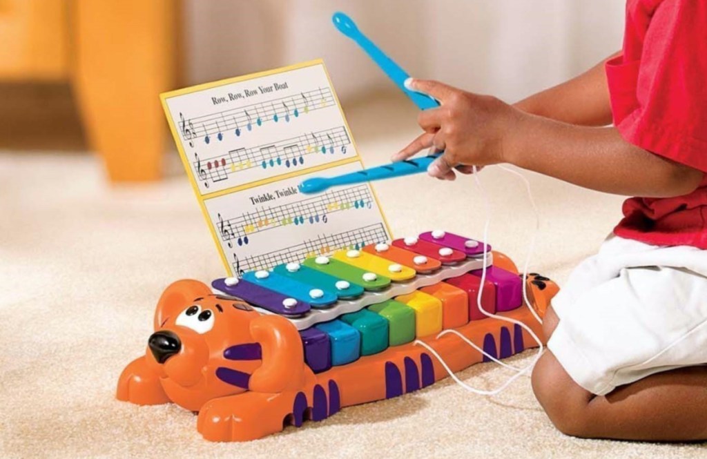 little boy playing on toy piano/xylophone on floor