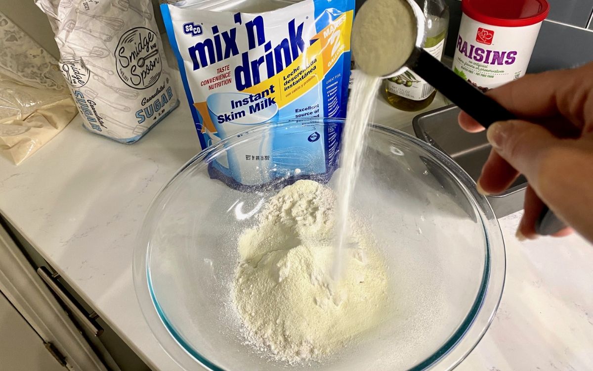 Pouring bread ingredients into a mixing bowl in the kitchen