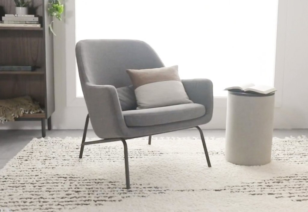 light grey lounge chair next to white side table on white area rug