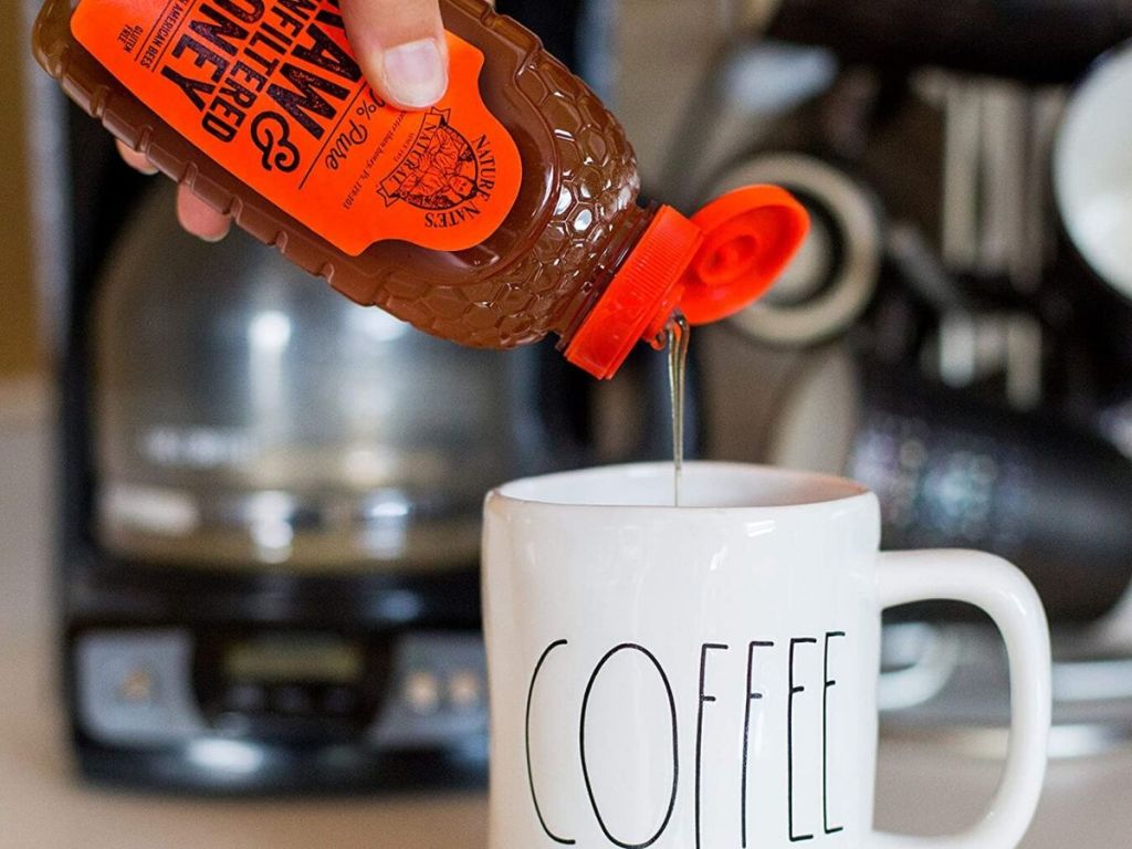 hand pouring honey into a coffee mug