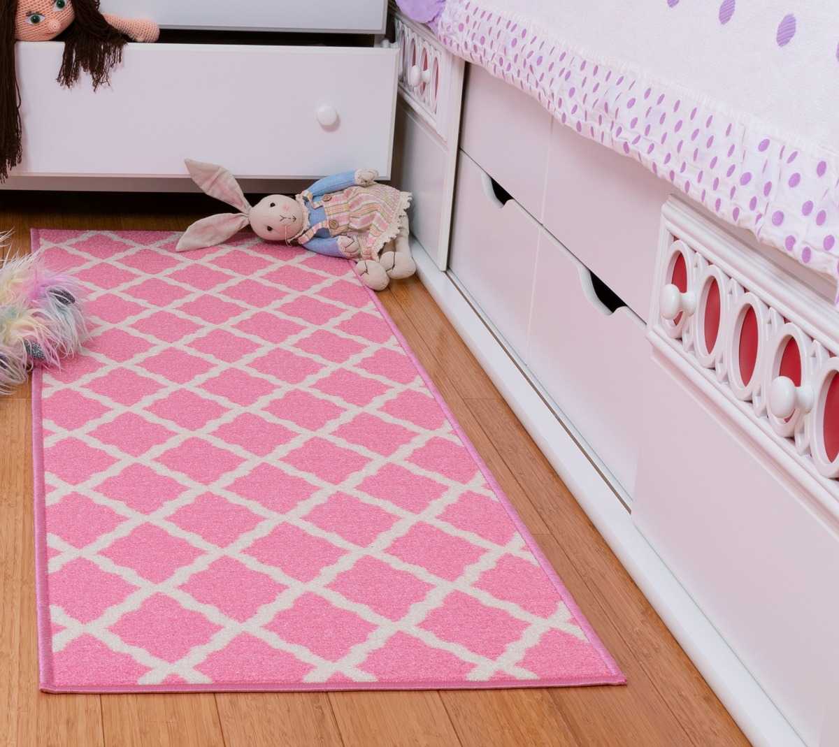 pink and white runner rug with trellis design next to a child's bed and toys