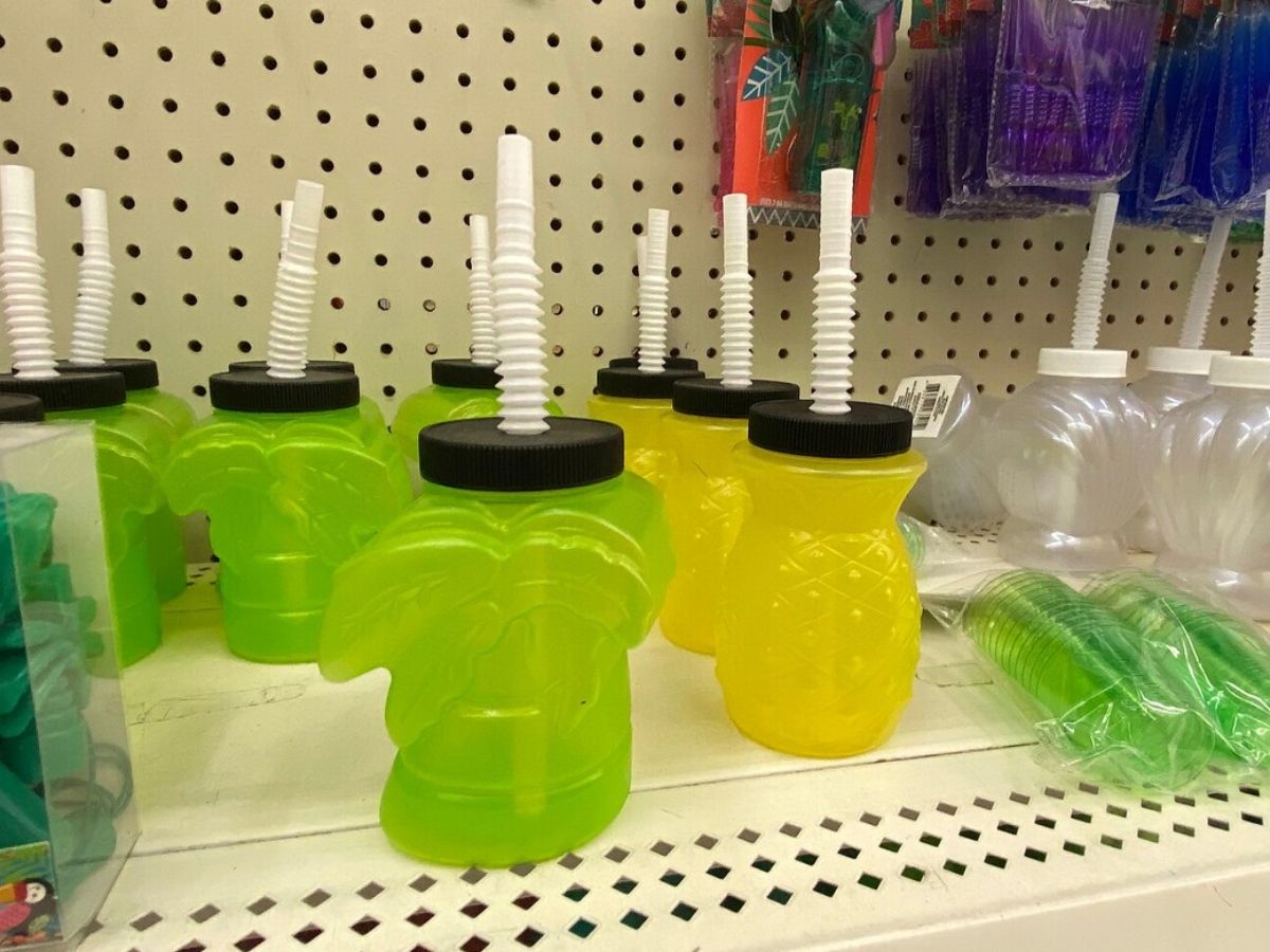 store shelf with plastic cups shaped likepalm trees and pineapples with lids and straws