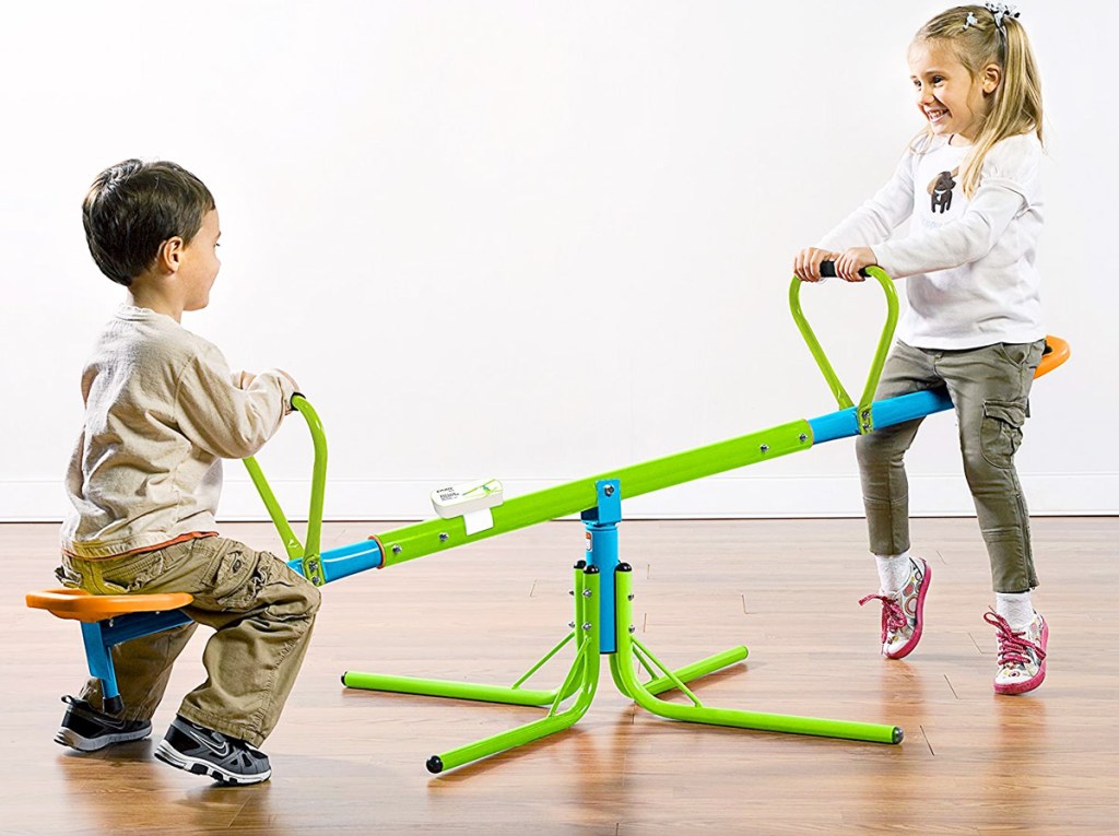 toddler boy and girl on green seesaw toy