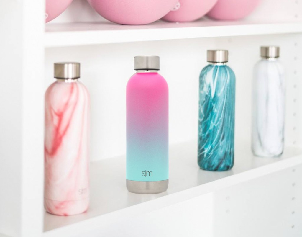 marble and ombre print water bottles sitting on a white shelf