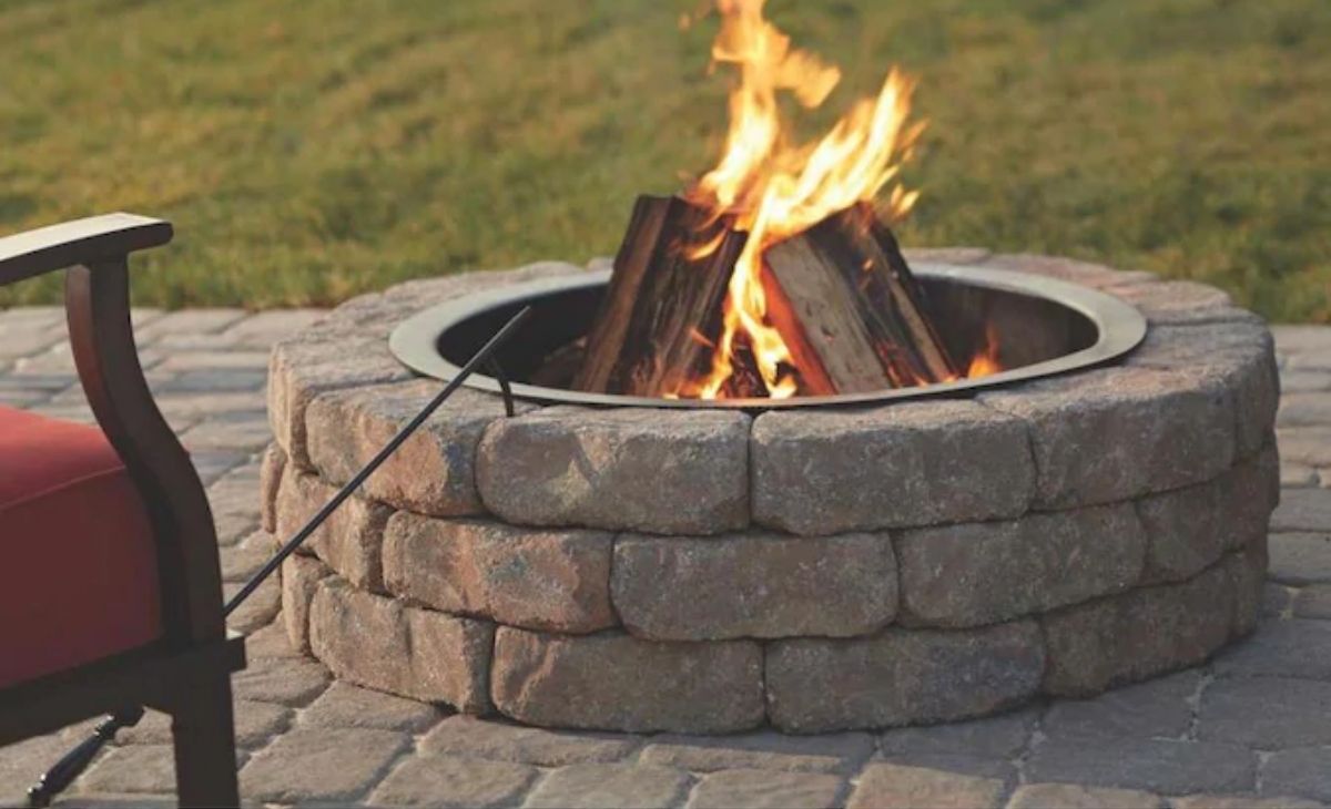 A fire burning in a stone fire pit outside 