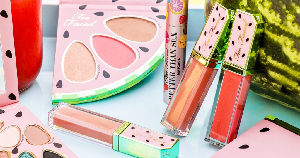 three tubes of pink lip gloss with watermelon printed lids next to a watermelon shaped eyeshadow palette