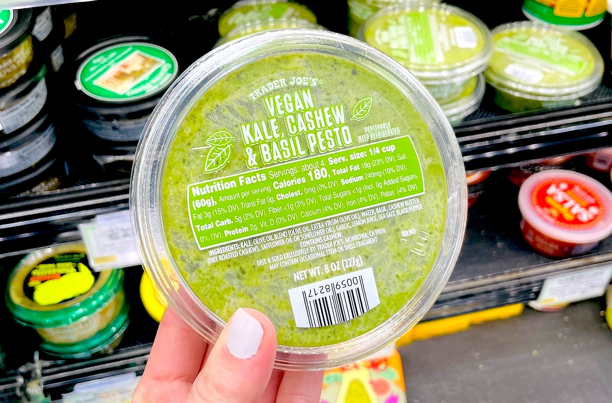 hand holding a tub of green pesto