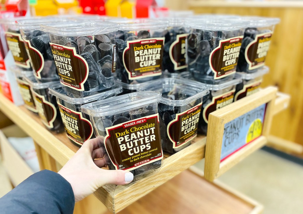 hand pulling bin of dark chocolate peanut butter cups off the shelf at trader joes