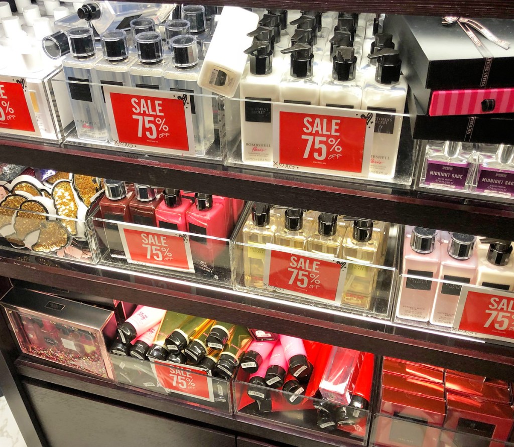 various different types of body lotions and sprays on store display shelfs with 75% off sale signs
