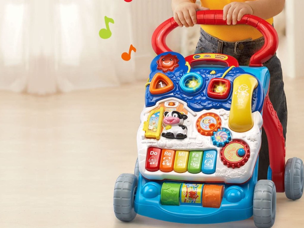 baby using toy walker on floor in home