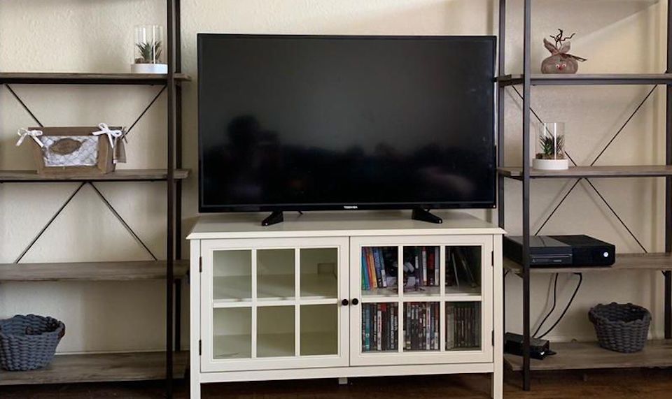 TV sitting on a TV stand with shelves next to it