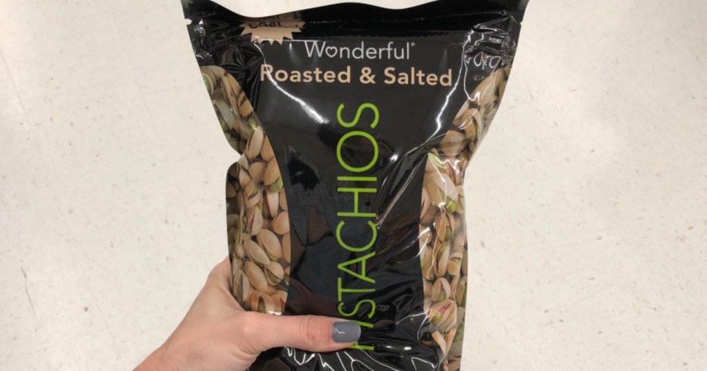 woman's hand holding large bag of roasted and salted pistachios