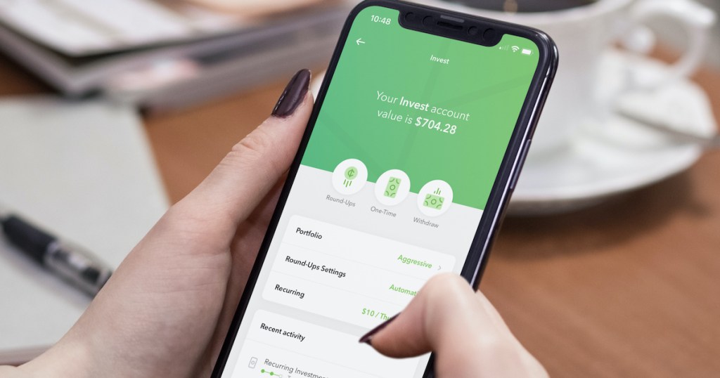 hands holding a phone with acorns investing app on screen