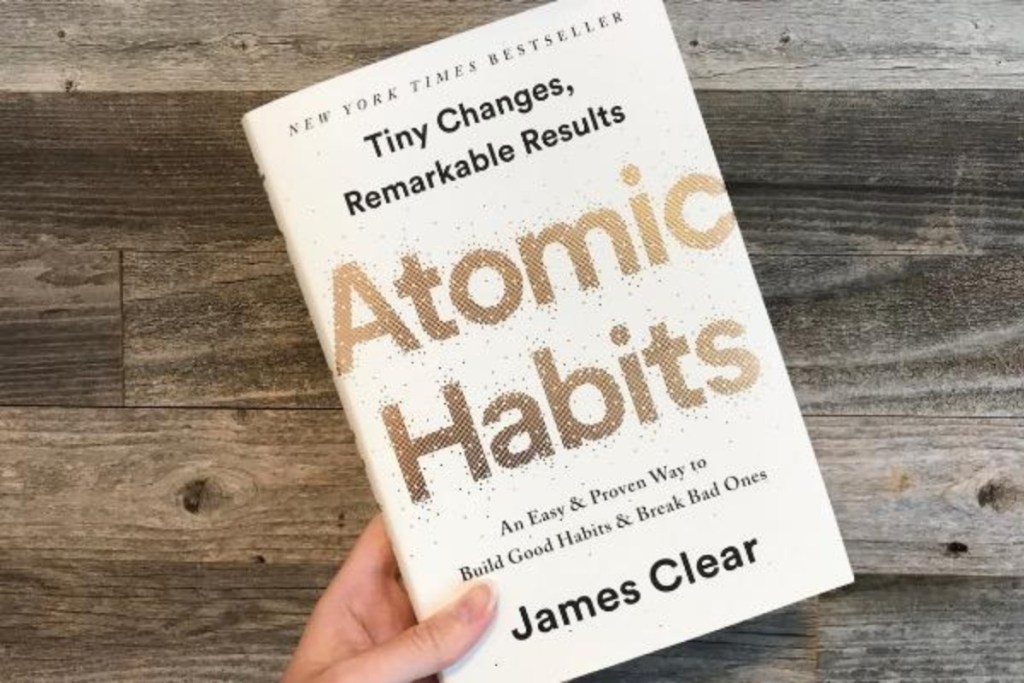 hand holding Atomic Habits hardback book