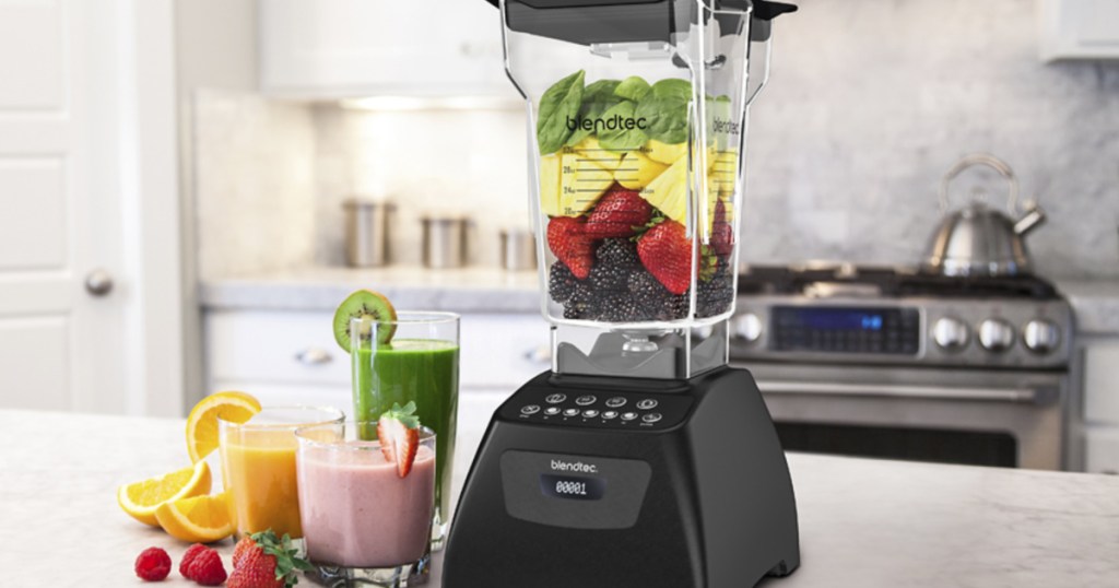blendtec blender sitting on kitchen counter next to fruit and fresh smoothies