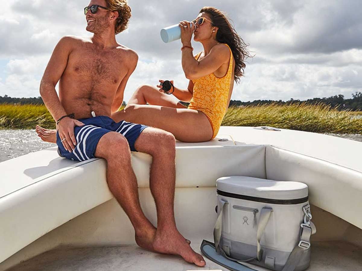 couple on a boat with a gray soft cooler
