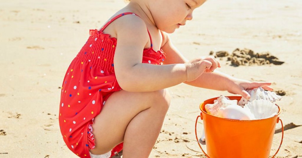 baby playing at beach with bucket