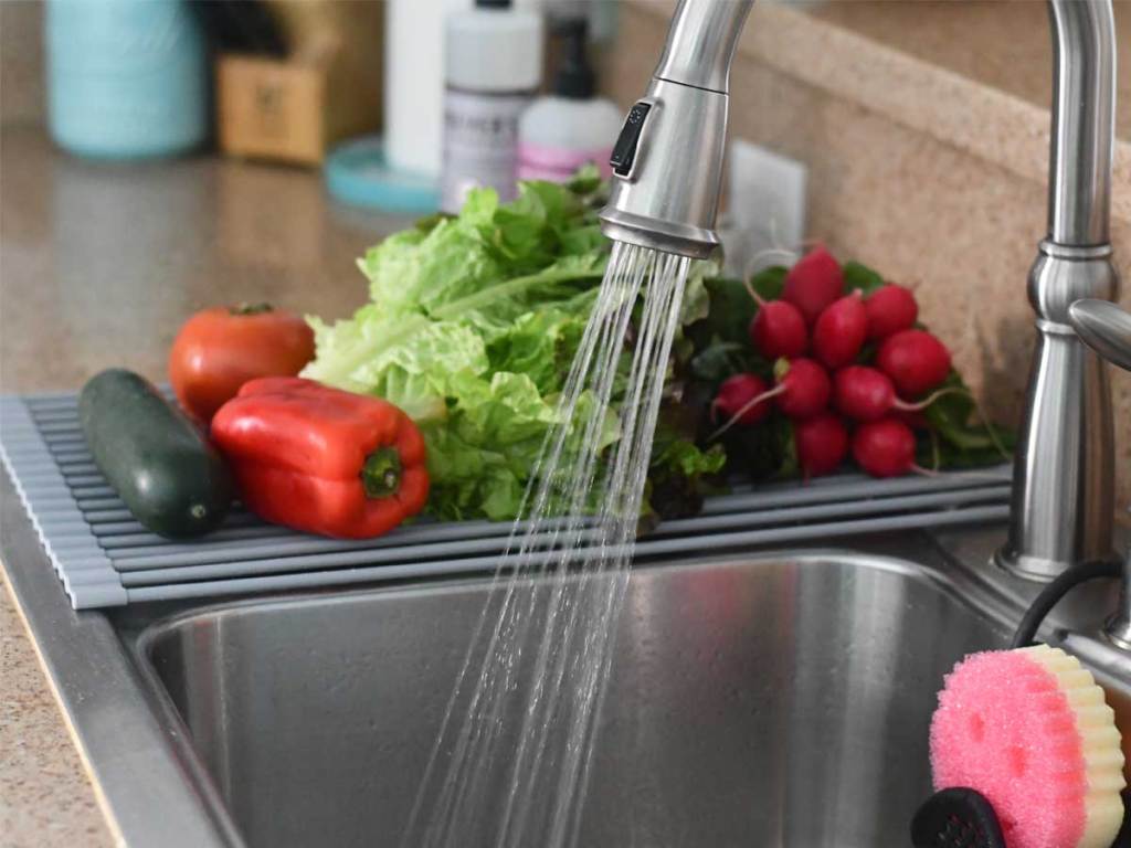 roll up drying rack on sink with vegetables in kitchen