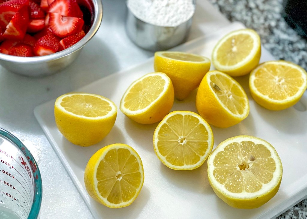 fresh lemons cut in half on cutting board