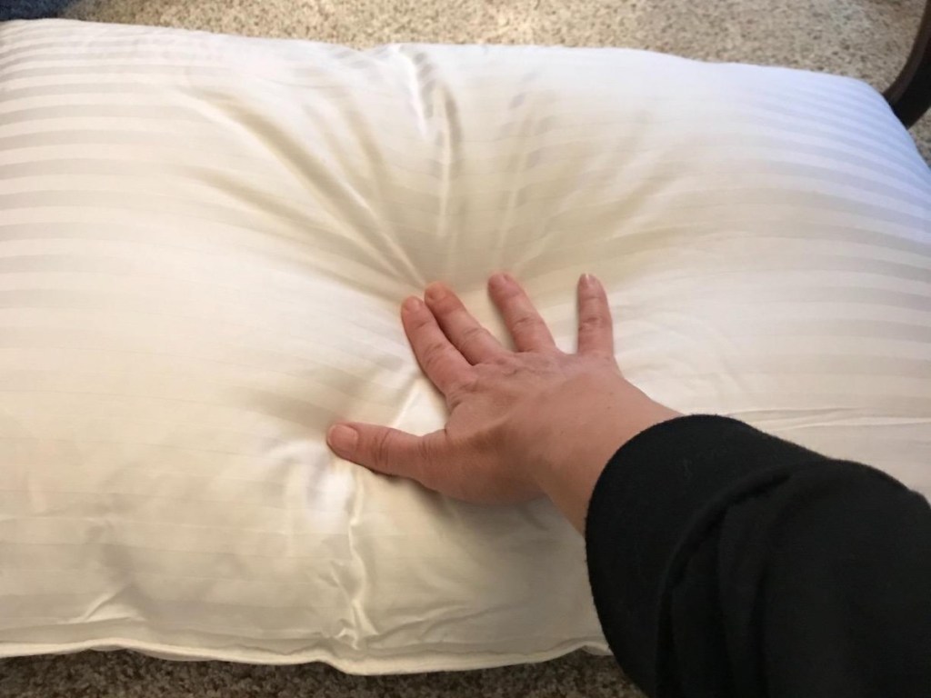 hand pushing down on white pillow